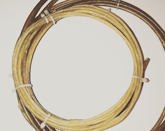 May include: Two coiled lengths of flexible, smooth material arranged in concentric circles. The inner coil is a light tan color, while the outer coil is a darker brown. Both coils are secured in place with small, white plastic zip ties.