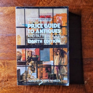May include: A vintage book cover with a colorful collage of antique items, including glassware, furniture, and a doll. The title reads "Price Guide to Antiques and Pattern Glass Eighth Edition" with the author's name "Robert W. Miller" at the bottom.