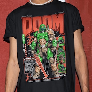 May include: Black t-shirt featuring a green and brown illustration of a character from the video game "Doom", with the word "DOOM" in large orange letters. The shirt also includes Japanese text and a red sword.