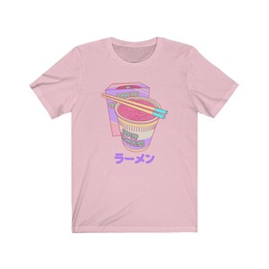 May include: Pink t-shirt with a cartoon illustration of a bowl of ramen noodles with chopsticks and a box of noodles that says "Roasted Noodles" and "Soup Noodles". The text "ラーメン" is printed below the bowl of noodles.