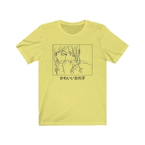 Może przedstawiać: Ż&oacute;łta koszulka z czarno-białym rysunkiem postaci anime, kt&oacute;ra płacze. Pod rysunkiem znajduje się napis "かわいい女の子".