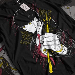 May include: Black t-shirt featuring a detailed anime-style illustration. The design depicts a character in a suit and tie holding a glowing yellow staff. The artwork includes red and yellow accents, with a matching character outline in the background.