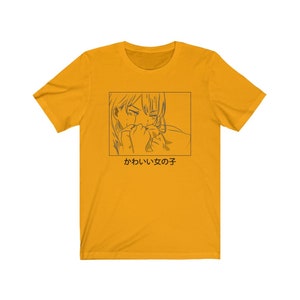Może przedstawiać: Ż&oacute;łta koszulka z czarno-białą ilustracją postaci anime z tekstem "かわいい女の子" w języku japońskim.