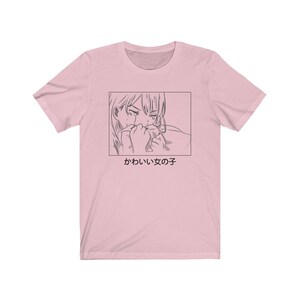 Może przedstawiać: R&oacute;żowa koszulka z czarno-białym rysunkiem płaczącej dziewczyny z anime. Pod rysunkiem znajduje się napis "かわいい女の子".