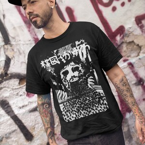 Puede incluir: Una camiseta negra con un estampado gr&aacute;fico blanco de una cara rodeada de una multitud de personas. El gr&aacute;fico tambi&eacute;n incluye texto japon&eacute;s.