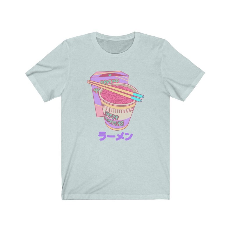 May include: A light blue t-shirt with a cartoon illustration of a pink and purple instant noodle cup with chopsticks and a box that says "Seasoned Noodles" and "Soup Noodles" in a pink and green font. The text "ラーメン" is printed in purple below the illustration.