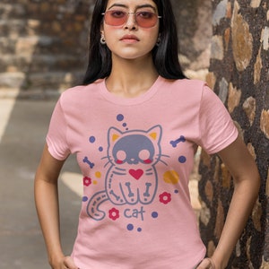 Peut inclure: Un t-shirt rose avec un motif de chat de dessin anim&eacute;. Le chat porte un c&oelig;ur et a des os pour les membres. Le texte "I cat" est imprim&eacute; sous le chat.