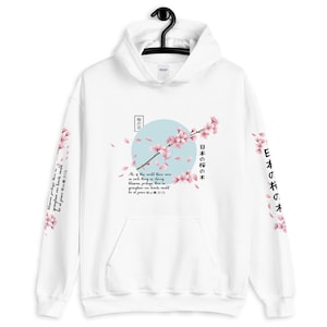 May include: White hoodie featuring a Japanese cherry blossom design with the text "日本の桜の木" (Japanese cherry blossom) and "桜の花" (cherry blossom) on the front. The sleeves display a repeating pattern of cherry blossoms.