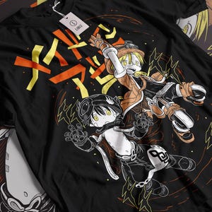 以下が含まれることがあります： 黒いTシャツ。アニメスタイルのイラストが特徴です。デザインは、オレンジと黄色の日本のテキストとグラフィック要素を背景に、黄色の目をした2人のキャラクターを特徴としています。「LARGE」と書かれたタグが付いています。