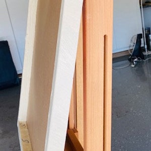 K&ouml;nnte beinhalten: Eine h&ouml;lzerne K&uuml;nstlerstaffelei mit einem Leinwandrahmen. Die Staffelei ist aus hellem Holz gefertigt und verf&uuml;gt &uuml;ber verstellbare Funktionen. Der Leinwandrahmen ist wei&szlig; und beige. Die Staffelei ist f&uuml;r Malerei und Kunstprojekte konzipiert.