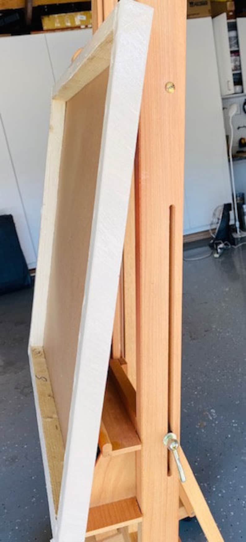K&ouml;nnte beinhalten: Eine h&ouml;lzerne K&uuml;nstlerstaffelei mit einem Leinwandrahmen. Die Staffelei ist aus hellem Holz gefertigt und verf&uuml;gt &uuml;ber verstellbare Funktionen. Der Leinwandrahmen ist wei&szlig; und beige. Die Staffelei ist f&uuml;r Malerei und Kunstprojekte konzipiert.