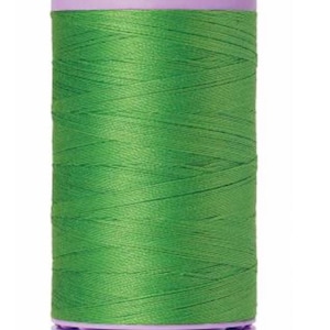 May include: A spool of green Mettler Silk-Finish thread with the text "GROUP Mettler SILK-FINISH" on the label. The spool is labeled "No. 50 500m/547yd".
