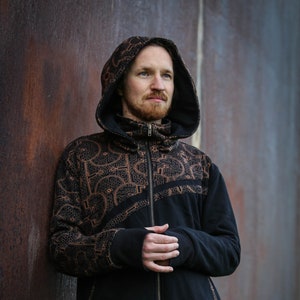 May include: A black hooded sweatshirt with a zipper closure and a brown geometric pattern. The sweatshirt has a high collar and a relaxed fit.