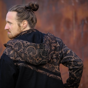 May include: A black hooded jacket with a brown geometric pattern. The jacket has a zipper closure and long sleeves.