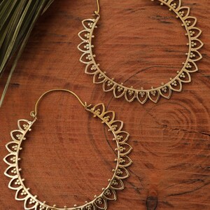 May include: A pair of gold hoop earrings with a delicate, intricate design. The earrings are made of metal and have a circular shape. They are perfect for adding a touch of elegance to any outfit.