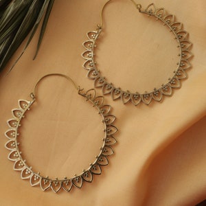 May include: A pair of gold hoop earrings with a delicate, intricate design. The earrings are made of metal and have a circular shape. They are perfect for adding a touch of elegance to any outfit.