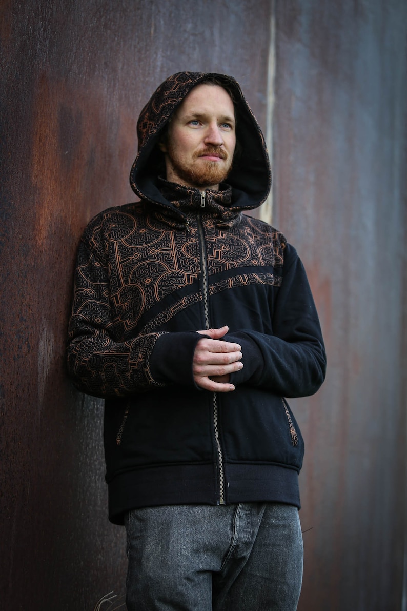 May include: A black hooded sweatshirt with a zipper closure and a brown geometric pattern. The sweatshirt has a high collar and a relaxed fit.