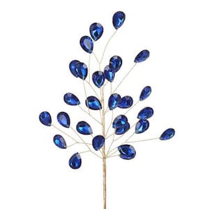 May include: A decorative stem with numerous teardrop-shaped, deep blue gemstones. The gemstones are attached to thin, gold-coloured wire branches, creating a floral or ornamental design. Suitable for floral arrangements or craft projects.