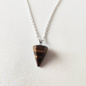 May include: A silver chain necklace featuring a brown, cone-shaped pendant. The pendant has a striped pattern and a polished finish. The necklace is displayed on a white surface.