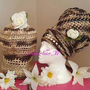 May include: Two crochet hats in shades of brown, tan, and black, adorned with white fabric flowers. One hat is on a mannequin head, the other is displayed separately. The hats have an open weave design. The text "Crochet Addict TW" is visible.