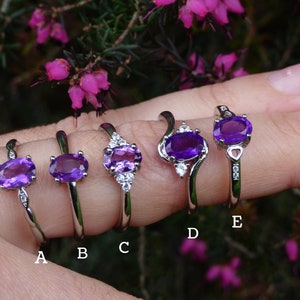 May include: Five silver rings with oval amethyst gemstones and small clear cubic zirconia accents. The rings are labeled A through E.