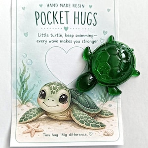 May include: A handmade resin Pocket Hugs card featuring a cartoon turtle illustration and a small, green resin turtle. The card reads "Little turtle, keep swimming - every wave makes you stronger."