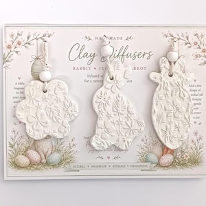 May include: Three white clay diffusers featuring embossed floral patterns in the shapes of a flower, a rabbit, and a carrot. Each piece is suspended by a white cord with a small white bead, mounted on a decorative card labelled Clay Diffusers.