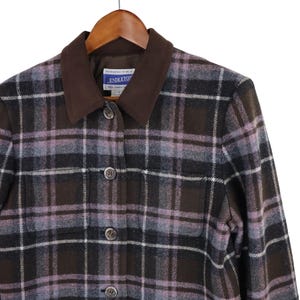 K&ouml;nnte beinhalten: Pendleton-Jacke mit braunem, schwarzem und lavendelfarbenem Karomuster, mit braunem Kragen und Knopfverschluss. Die Jacke h&auml;ngt an einem Holzb&uuml;gel. Das Pendleton-Etikett ist sichtbar.