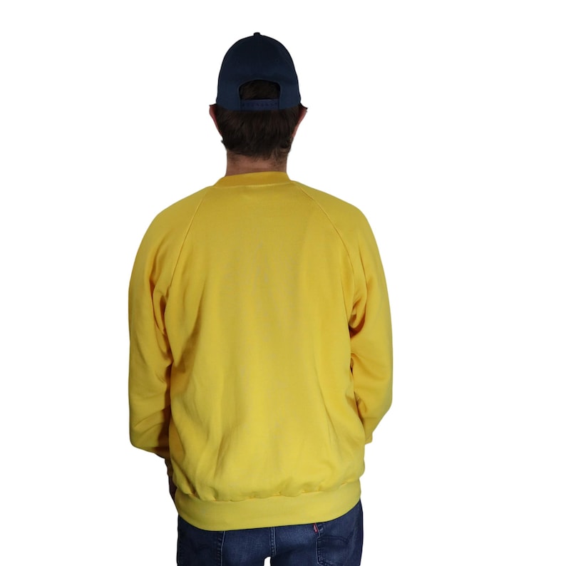 Puede incluir: Una sudadera amarilla de cuello redondo y mangas largas. La sudadera es lisa, sin gr&aacute;ficos ni texto.