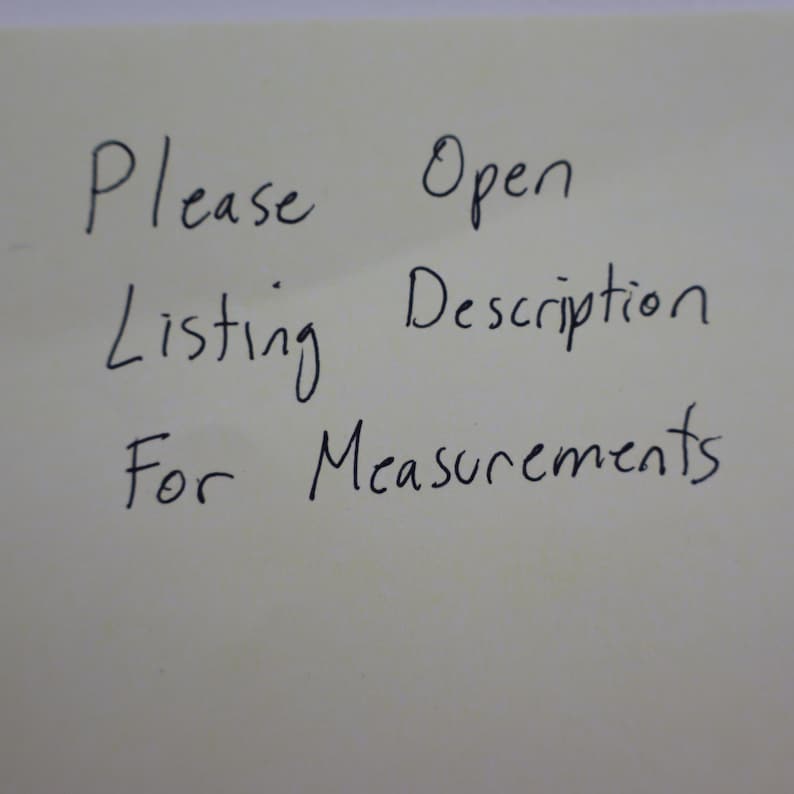 K&ouml;nnte beinhalten: Eine handschriftliche Notiz auf cremefarbenem Papier. Der Text lautet "Bitte Beschreibung &ouml;ffnen f&uuml;r Ma&szlig;e" in schwarzer Tinte. Das Papier ist leicht zerknittert.