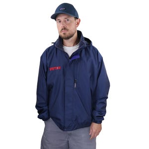Könnte beinhalten: Marineblaue Kapuzenjacke mit dem Wort "STRIPTEASE" in roter Schrift. Die Jacke hat einen Reißverschluss und eine kleine Tasche. Die Person auf dem Bild trägt auch eine marineblaue Baseballkappe.