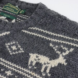 May include: A gray knitted sweater with a white reindeer pattern. The sweater has a crew neck and is made of a soft, warm material. The label on the sweater reads "G.C.  Pearson Co. Seattle."