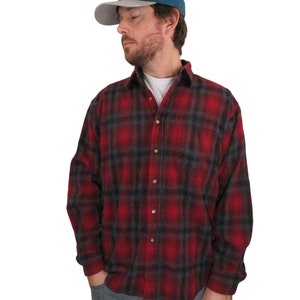 Puede incluir: Una camisa de franela a cuadros rojos y negros con cierre de botones y mangas largas. La camisa la lleva puesta una persona que lleva una gorra de béisbol azul con la palabra "Patagonia" en ella.