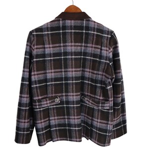 K&ouml;nnte beinhalten: Ein brauner, schwarzer und lavendelfarbener Blazer mit Karomuster, einem braunen Kragen und zwei Vordertaschen. Der Blazer h&auml;ngt an einem Holzb&uuml;gel.