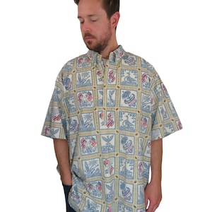 Puede incluir: Una camisa de manga corta con botones, fondo blanco y un patrón de cuadrados azules, rojos y dorados con imágenes de banderas americanas, águilas y las palabras "America" y "United States".