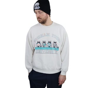 Puede incluir: Una sudadera blanca con un gráfico de cuatro osos de dibujos animados con gafas de sol y sentados en sillas de jardín. El gráfico también incluye el texto "Brigham Young University".