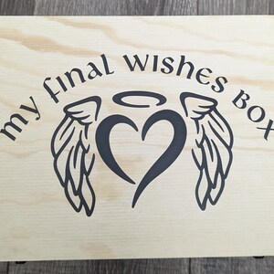 May include: A wooden box with a black and white design of wings, a heart, and a halo. The text "my final wishes box" is printed on the box.