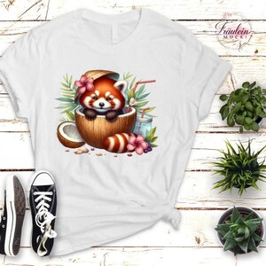 Könnte beinhalten: Weißes T-Shirt mit einem Cartoon-Roten Panda in einer Kokosnuss, umgeben von tropischen Blumen und einem Getränk. Das Design umfasst eine halbe Kokosnuss, Blätter und ein rot-weiß gestreiftes Objekt.