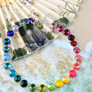 May include: A rainbow crystal necklace with a silver chain and round, faceted crystals in shades of purple, blue, green, yellow, orange, and red.