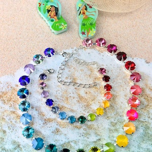 May include: Two necklaces with rainbow coloured crystal beads on a white and blue background. The necklaces are made of silver chain and have a clasp.