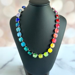 May include: A rainbow crystal necklace with a silver chain and round, faceted crystals in shades of purple, blue, green, yellow, orange, and red.
