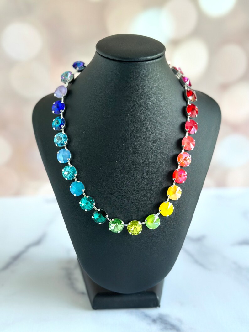 May include: A rainbow crystal necklace with a silver chain and round, faceted crystals in shades of purple, blue, green, yellow, orange, and red.