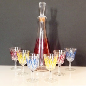 Puede incluir: Un juego de seis vasos de chupito de vidrio transparente con diseños geométricos coloridos y una decantador a juego con un tapón de corcho.
