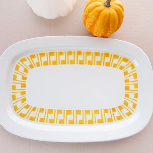 Könnte beinhalten: Weiße ovale Servierplatte mit gelber geometrischer Bordüre.