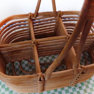 May include: A brown wicker basket with a handle, divided into four sections. The basket is made of woven rattan and has a natural finish.