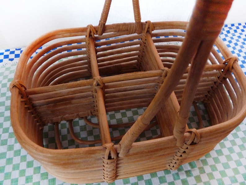 May include: A brown wicker basket with a handle, divided into four sections. The basket is made of woven rattan and has a natural finish.