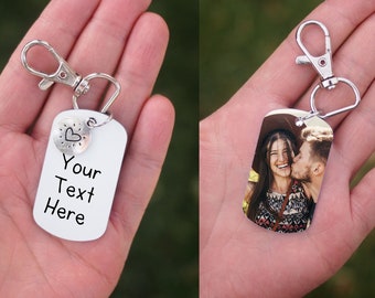 Könnte beinhalten: Zwei silberne Schlüsselanhänger mit einem silbernen Verschluss. Ein Schlüsselanhänger hat einen silbernen Anhänger mit einem Herzen und dem Text "Your Text Here". Der andere Schlüsselanhänger hat ein Foto eines Paares.