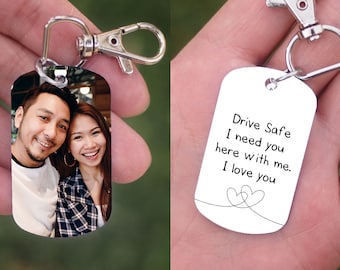 Könnte beinhalten: Ein silberner Schlüsselanhänger mit einem Foto eines Paares auf der einen Seite und dem Text "Fahr vorsichtig Ich brauche dich hier bei mir. Ich liebe dich" mit zwei ineinander verschlungenen Herzen auf der anderen Seite.