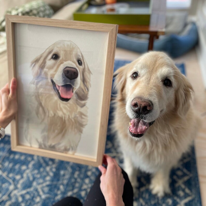 K&ouml;nnte beinhalten: Ein gerahmtes Aquarellbild eines Golden Retriever Hundes. Der Hund schaut mit leicht ge&ouml;ffnetem Maul in die Kamera und zeigt seine Zunge. Das Bild ist in einem hellen Holzrahmen.