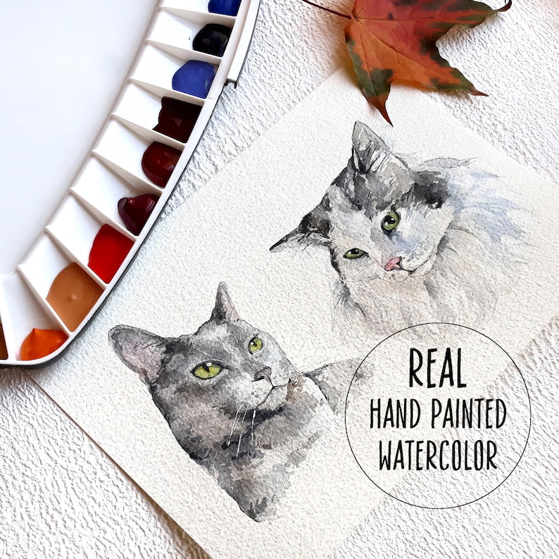 May include: Watercolour painting of two cats. One cat is grey and the other is white and grey. The painting is signed "REAL HAND PAINTED WATERCOLOUR".